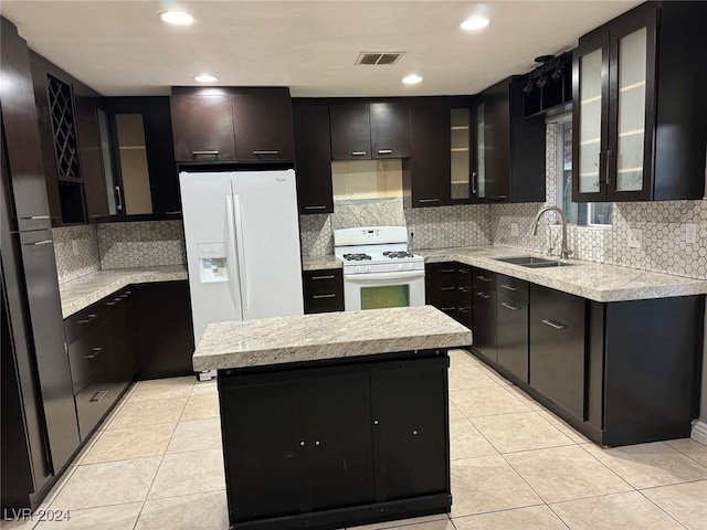 kitchen with decorative backsplash, white appliances, sink, light tile patterned floors, and a center island