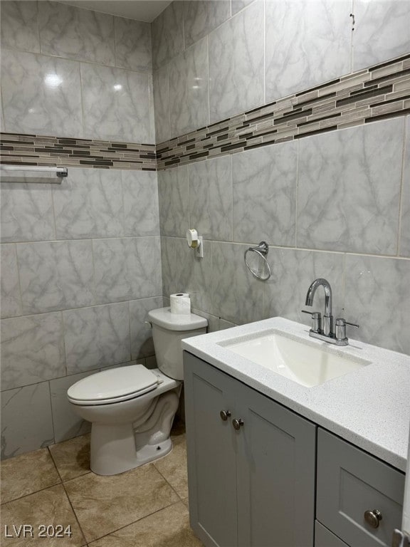 bathroom featuring tile patterned flooring, vanity, tile walls, and toilet