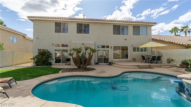 rear view of house with pool water feature, a patio area, and a fenced in pool