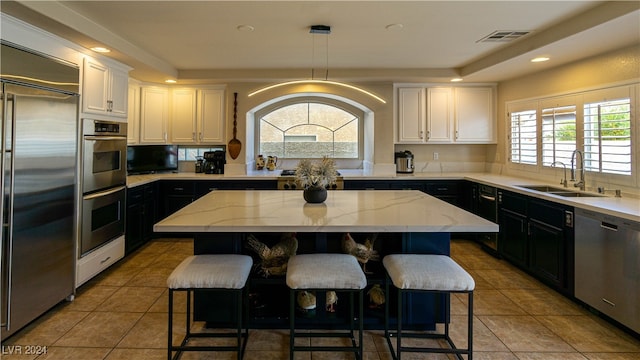 kitchen featuring a kitchen island, sink, stainless steel appliances, and hanging light fixtures