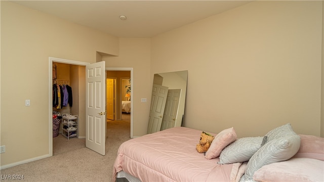 bedroom featuring a walk in closet, a closet, and light colored carpet