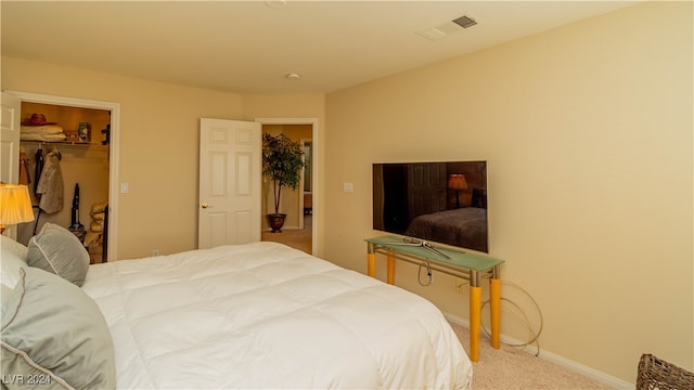 carpeted bedroom featuring a walk in closet and a closet