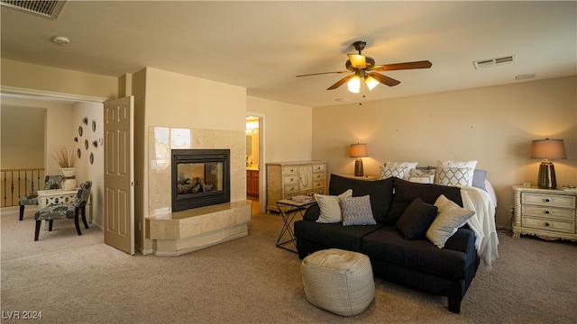 carpeted living room with ceiling fan and a tiled fireplace