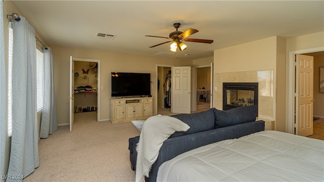 carpeted bedroom featuring ceiling fan, a spacious closet, a fireplace, and a closet