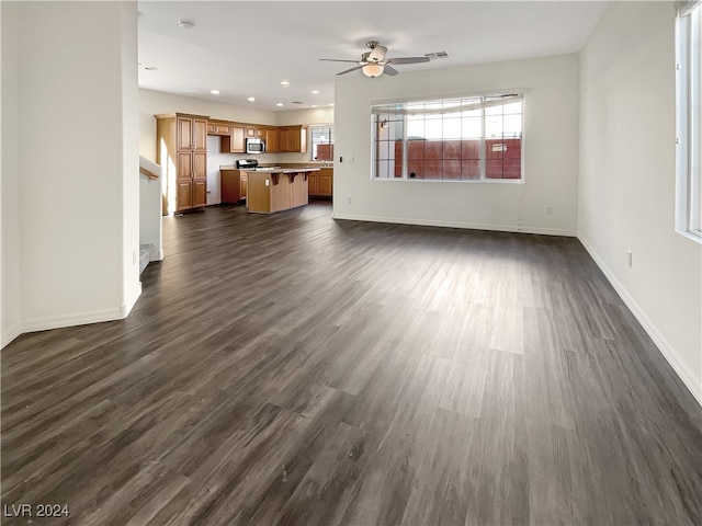 unfurnished living room featuring ceiling fan and dark hardwood / wood-style flooring