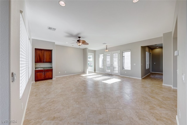 unfurnished living room with ceiling fan and french doors