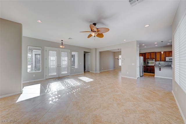 unfurnished living room featuring french doors, light tile patterned floors, and ceiling fan with notable chandelier