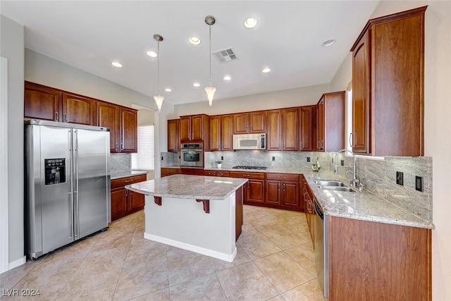 kitchen featuring sink, hanging light fixtures, stainless steel appliances, light stone counters, and a kitchen island