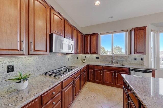 kitchen featuring light stone countertops, sink, tasteful backsplash, light tile patterned flooring, and appliances with stainless steel finishes