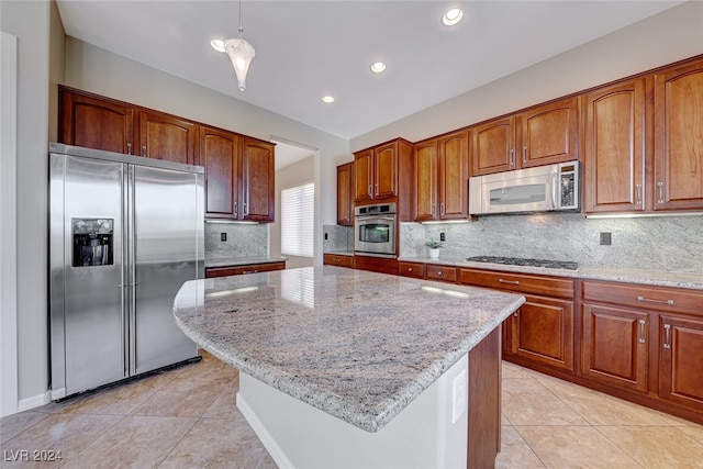 kitchen featuring decorative backsplash, light stone counters, a kitchen island, and appliances with stainless steel finishes