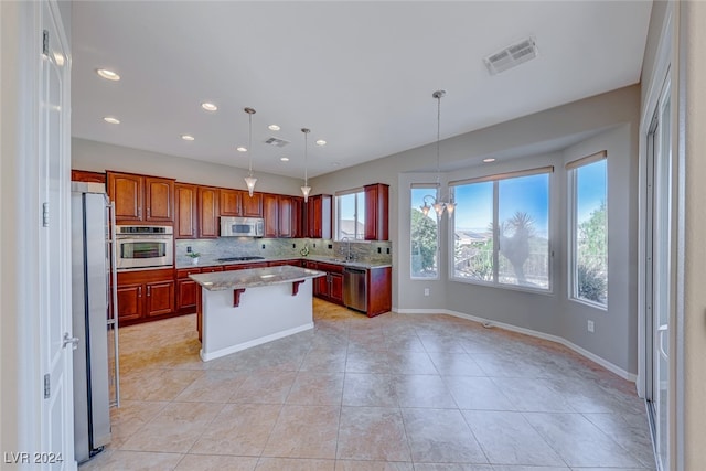 kitchen with light stone countertops, appliances with stainless steel finishes, tasteful backsplash, pendant lighting, and a center island