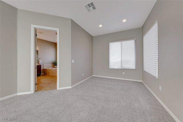 unfurnished bedroom with connected bathroom and light carpet