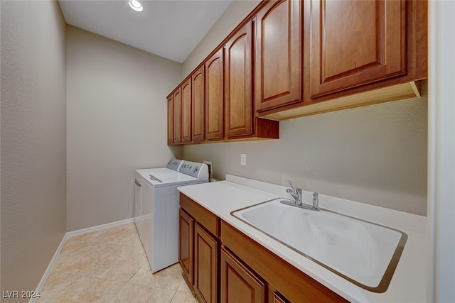 laundry room with washing machine and clothes dryer, sink, light tile patterned floors, and cabinets