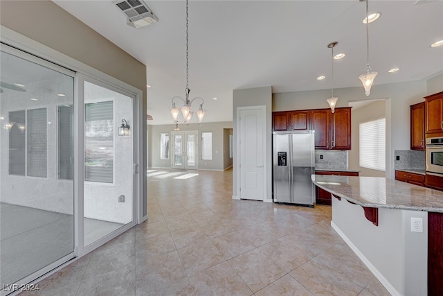 kitchen with decorative light fixtures, light stone countertops, decorative backsplash, and appliances with stainless steel finishes