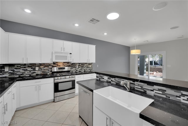 kitchen featuring decorative backsplash, light tile patterned floors, appliances with stainless steel finishes, decorative light fixtures, and white cabinetry