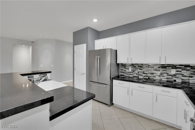 kitchen featuring stainless steel fridge, white cabinetry, and sink