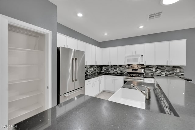 kitchen featuring backsplash, white cabinetry, and appliances with stainless steel finishes