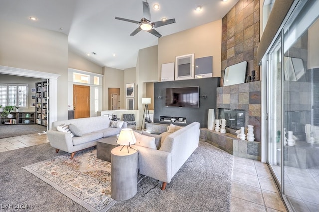 living room featuring high vaulted ceiling, light tile patterned floors, a tile fireplace, and ceiling fan