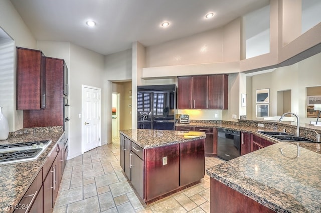 kitchen featuring sink, dark stone countertops, a high ceiling, black appliances, and a kitchen island