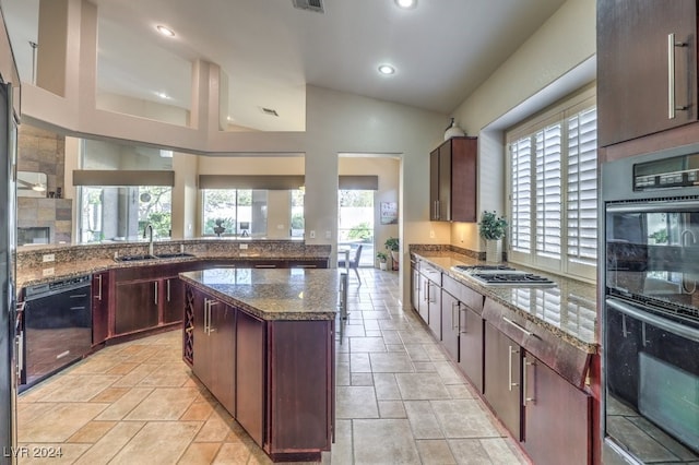 kitchen with sink, a kitchen island, black appliances, stone countertops, and vaulted ceiling