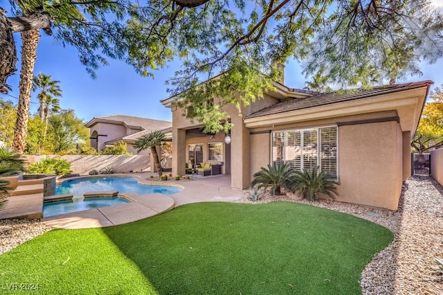 rear view of house featuring a swimming pool with hot tub, a yard, and a patio area