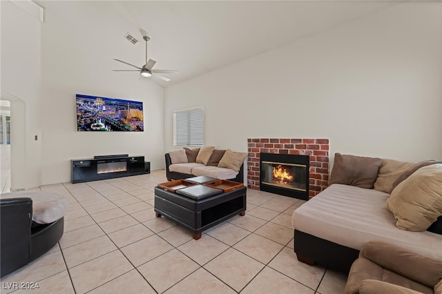 tiled living room featuring ceiling fan, a towering ceiling, and a fireplace