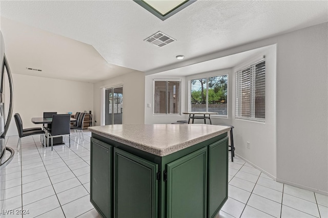 kitchen with a textured ceiling, a center island, light tile patterned floors, and green cabinetry