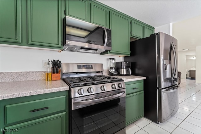 kitchen with green cabinets, light tile patterned floors, and appliances with stainless steel finishes