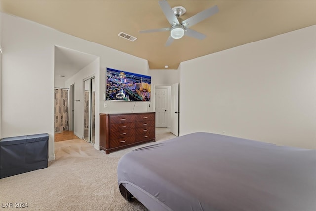 bedroom with ceiling fan, light carpet, and connected bathroom