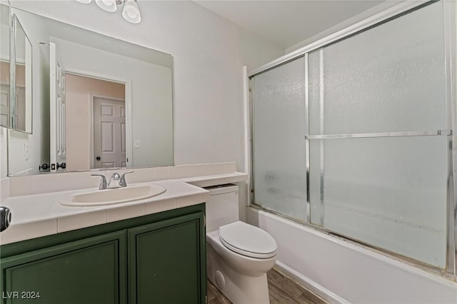 full bathroom featuring hardwood / wood-style floors, vanity, toilet, and enclosed tub / shower combo