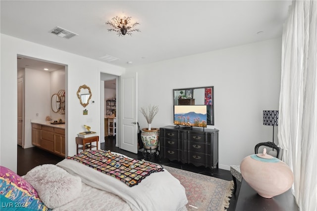 bedroom featuring ensuite bath and dark wood-type flooring