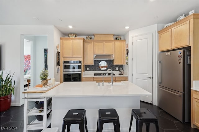 kitchen featuring sink, light brown cabinetry, a kitchen island with sink, and appliances with stainless steel finishes