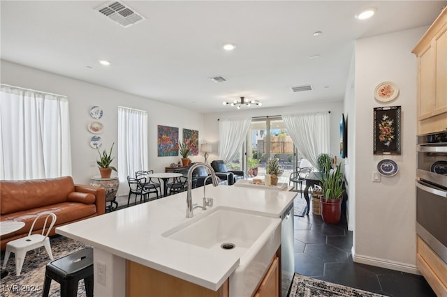 kitchen with a kitchen bar, dark tile patterned floors, sink, a center island with sink, and dishwasher