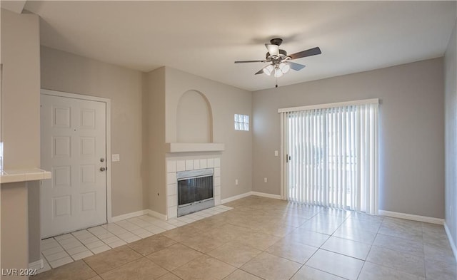 unfurnished living room featuring a tile fireplace, ceiling fan, and light tile patterned floors