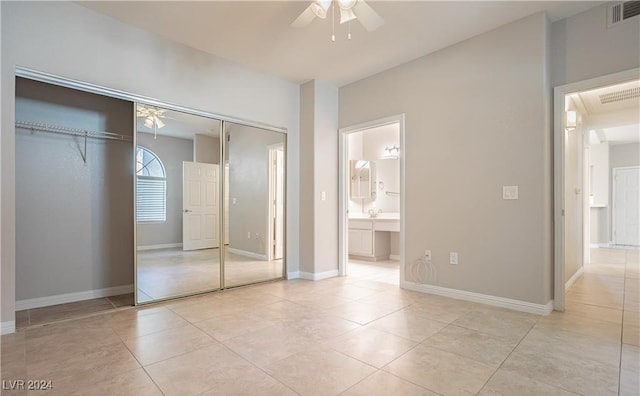 unfurnished bedroom featuring light tile patterned floors, ensuite bathroom, a closet, and ceiling fan