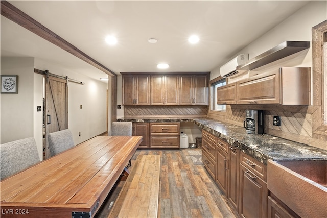 kitchen featuring backsplash, a wall mounted air conditioner, a barn door, hardwood / wood-style floors, and recessed lighting