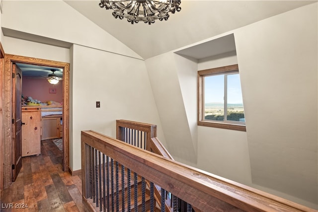 hall with a chandelier, an upstairs landing, dark wood-style floors, and vaulted ceiling