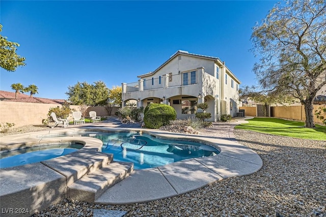 rear view of house featuring a patio, a balcony, and a swimming pool with hot tub