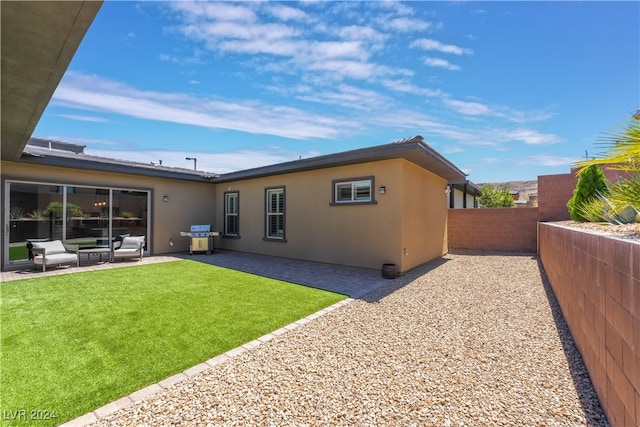 back of property with a patio, an outdoor hangout area, and a lawn