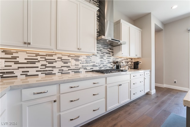 kitchen with white cabinets, wall chimney exhaust hood, light stone countertops, and dark wood-type flooring