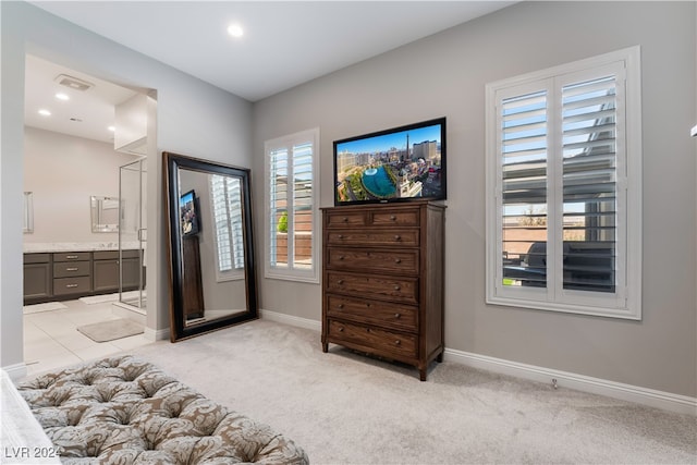 bedroom featuring light carpet and connected bathroom