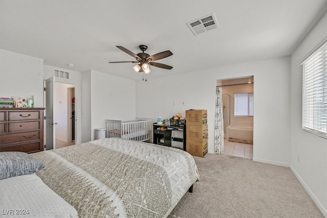 bedroom with ensuite bathroom, ceiling fan, and light carpet