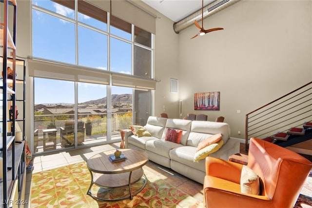 living room featuring a mountain view, a high ceiling, light tile patterned floors, and a healthy amount of sunlight