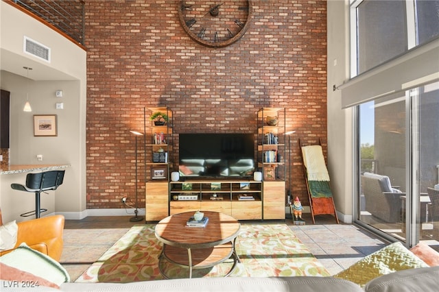 living room featuring a towering ceiling and brick wall