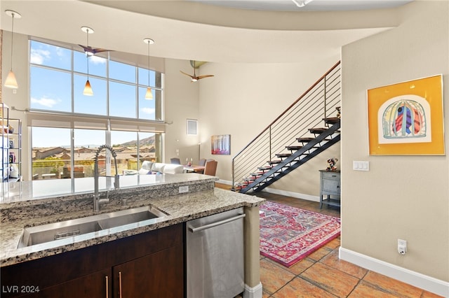 kitchen with light stone counters, stainless steel dishwasher, ceiling fan, sink, and hanging light fixtures