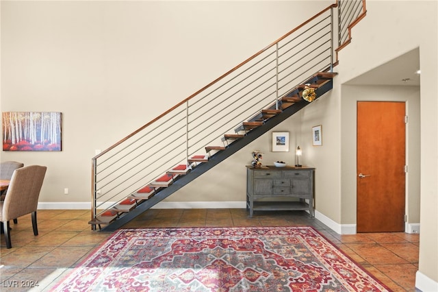 stairs with tile patterned flooring and a towering ceiling