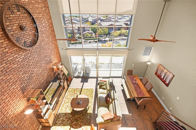 living room featuring tile patterned floors, ceiling fan, and a high ceiling