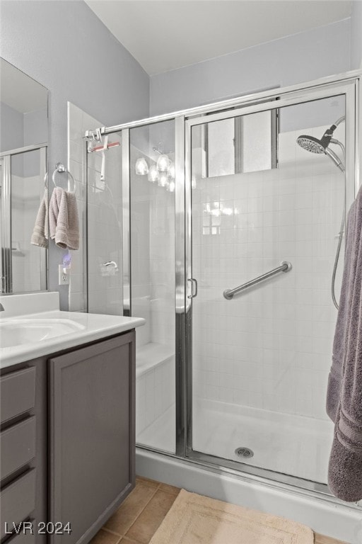 bathroom featuring vanity, a shower with shower door, and tile patterned floors