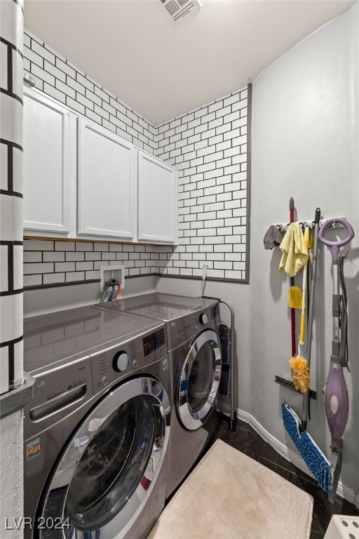 clothes washing area featuring cabinets and washing machine and clothes dryer