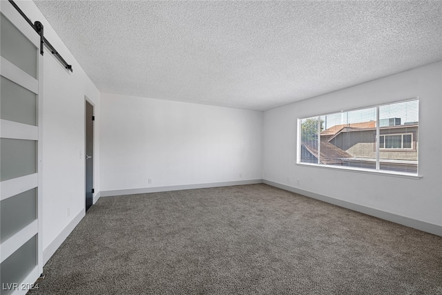 spare room featuring a barn door, carpet floors, and a textured ceiling